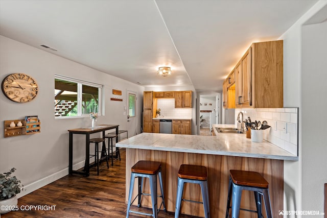 15250 Evergreen Ridge St, Anchorage, AK 99516 - kitchen with decorative backsplash, a peninsula, dark wood-type flooring, stainless steel dishwasher, and a breakfast bar area