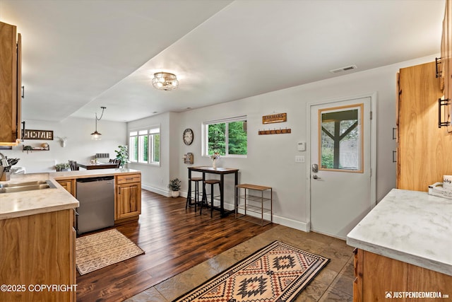 15250 Evergreen Ridge St, Anchorage, AK 99516 - kitchen with stainless steel dishwasher, light countertops, a peninsula, hanging light fixtures, and brown cabinetry