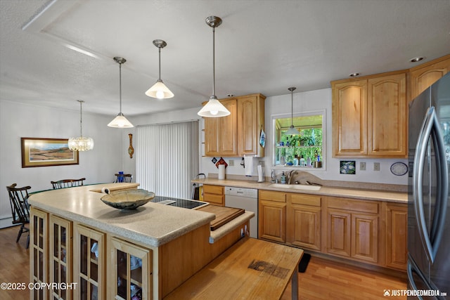 3217 Purdue St, Anchorage, AK 99508 - kitchen featuring freestanding refrigerator, dishwasher, a center island, light wood-style flooring, and hanging light fixtures