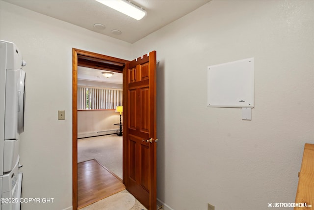 3217 Purdue St, Anchorage, AK 99508 - corridor featuring a baseboard heating unit and stacked washing machine and dryer