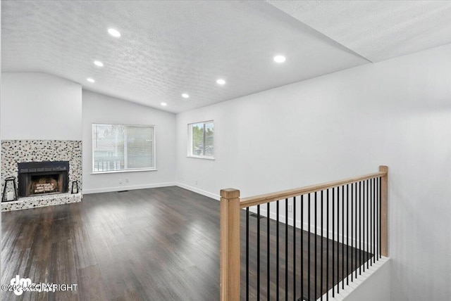 1928 Commodore Dr, Anchorage, AK 99507 - unfurnished living room featuring recessed lighting, wood finished floors, lofted ceiling, a tiled fireplace, and a textured ceiling