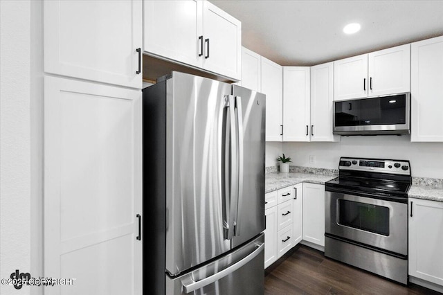 1928 Commodore Dr, Anchorage, AK 99507 - kitchen featuring appliances with stainless steel finishes, white cabinetry, dark wood-type flooring, light stone countertops, and recessed lighting