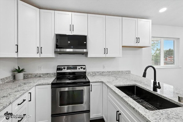 1928 Commodore Dr, Anchorage, AK 99507 - kitchen featuring appliances with stainless steel finishes, white cabinetry, recessed lighting, and light stone countertops