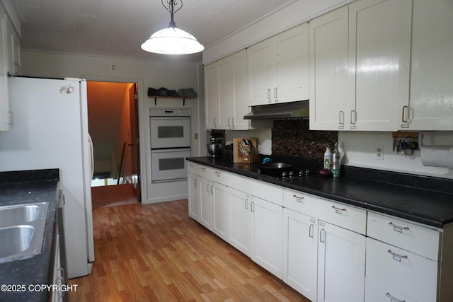 2600 Birch St, Seward, AK 99664 - kitchen with white appliances, under cabinet range hood, dark countertops, light wood-style flooring, and white cabinetry