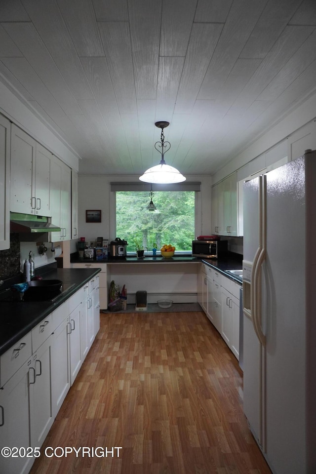 2600 Birch St, Seward, AK 99664 - kitchen with white fridge with ice dispenser, dark countertops, stainless steel microwave, white cabinets, and light wood-type flooring