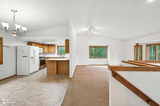 840 N Voss Cir, Wasilla, AK 99623 - kitchen featuring white appliances, lofted ceiling, brown cabinets, open floor plan, and a chandelier