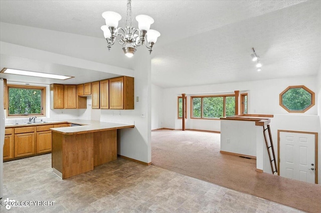 840 N Voss Cir, Wasilla, AK 99623 - kitchen with a peninsula, a textured ceiling, open floor plan, a chandelier, and brown cabinetry