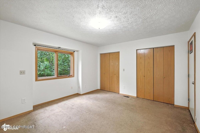 840 N Voss Cir, Wasilla, AK 99623 - unfurnished bedroom featuring multiple closets, light carpet, and a textured ceiling