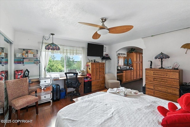 35485 Bluff Ct, Sterling, AK 99672 - bedroom with arched walkways, a desk, wood finished floors, ceiling fan, and a textured ceiling