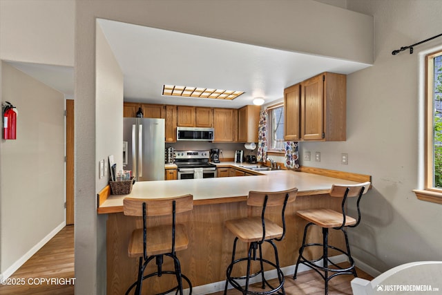 5170 Merle Cir, Anchorage, AK 99507 - kitchen featuring appliances with stainless steel finishes, light wood-style floors, healthy amount of natural light, and brown cabinets