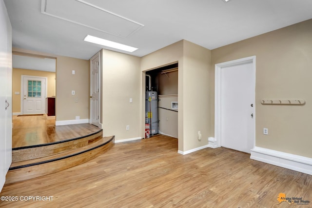 9601 Carlson Rd, Anchorage, AK 99507 - empty room with secured water heater, light wood-type flooring, and attic access