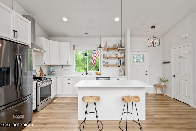 3200 E Woodruff Loop, Wasilla, AK 99654 - kitchen with appliances with stainless steel finishes, a breakfast bar area, backsplash, a center island, and light wood-style floors