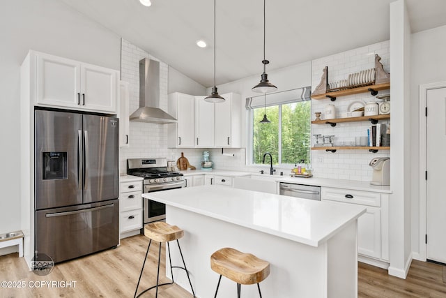 3200 E Woodruff Loop, Wasilla, AK 99654 - kitchen featuring stainless steel appliances, wall chimney range hood, light wood-type flooring, a breakfast bar, and backsplash