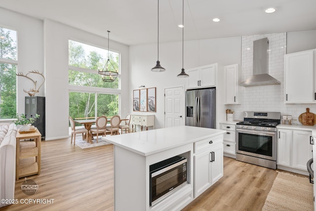 3200 E Woodruff Loop, Wasilla, AK 99654 - kitchen with wall chimney range hood, appliances with stainless steel finishes, a high ceiling, tasteful backsplash, and light countertops