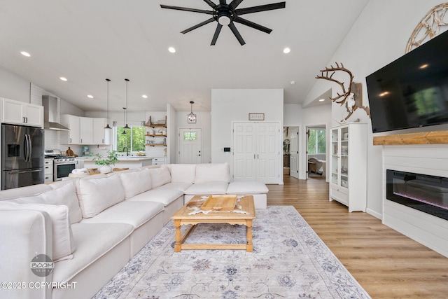 3200 E Woodruff Loop, Wasilla, AK 99654 - living area featuring a ceiling fan, light wood-style flooring, high vaulted ceiling, recessed lighting, and a glass covered fireplace