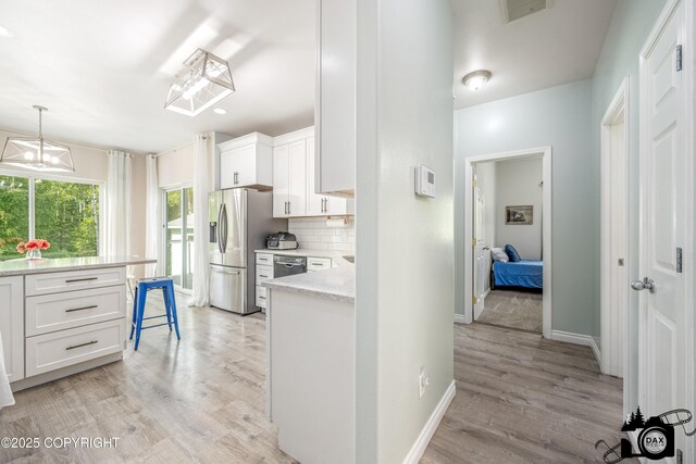 4228 E Serendipity Loop, Wasilla, AK 99654 - kitchen with stainless steel fridge, white cabinetry, light wood-style floors, backsplash, and dishwasher