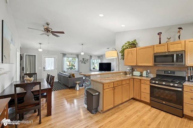 196 W Fairview Ave, Homer, AK 99603 - kitchen with stainless steel appliances, open floor plan, light wood-type flooring, light brown cabinets, and a ceiling fan