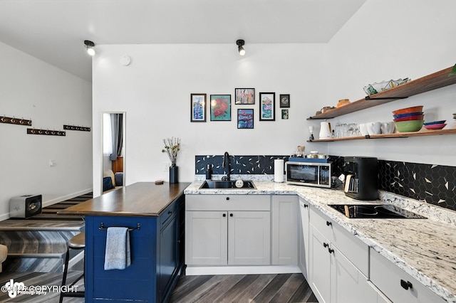 196 W Fairview Ave, Homer, AK 99603 - kitchen featuring stainless steel microwave, black electric stovetop, dark wood-style floors, a peninsula, and a kitchen bar