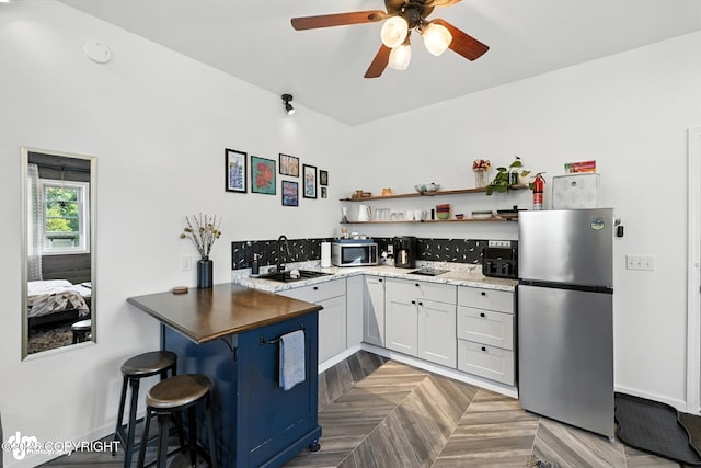 196 W Fairview Ave, Homer, AK 99603 - kitchen with stainless steel appliances, a ceiling fan, open shelves, a kitchen bar, and white cabinets