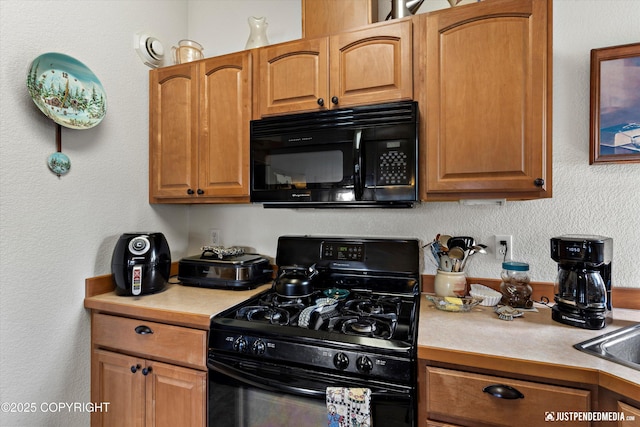 13693 E Guernsey Ln, Palmer, AK 99645 - kitchen with black appliances, light countertops, a textured wall, and brown cabinets
