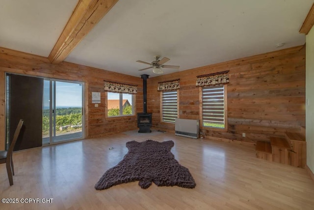 17751 Arcturus Loop, Ninilchik, AK 99639 - unfurnished room featuring a wood stove, wood finished floors, wood walls, a ceiling fan, and beam ceiling