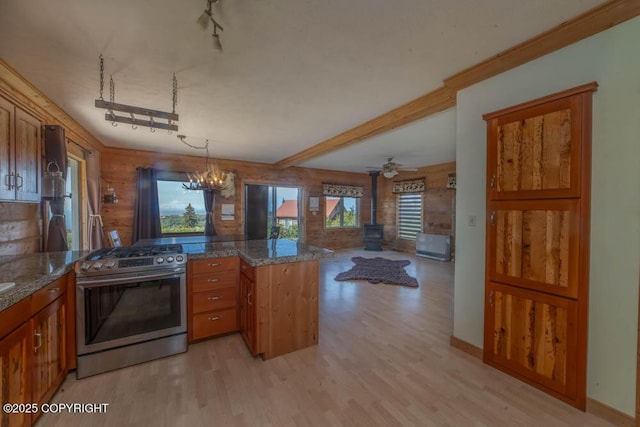 17751 Arcturus Loop, Ninilchik, AK 99639 - kitchen featuring stainless steel gas range oven, a peninsula, brown cabinets, a wood stove, and light wood-type flooring