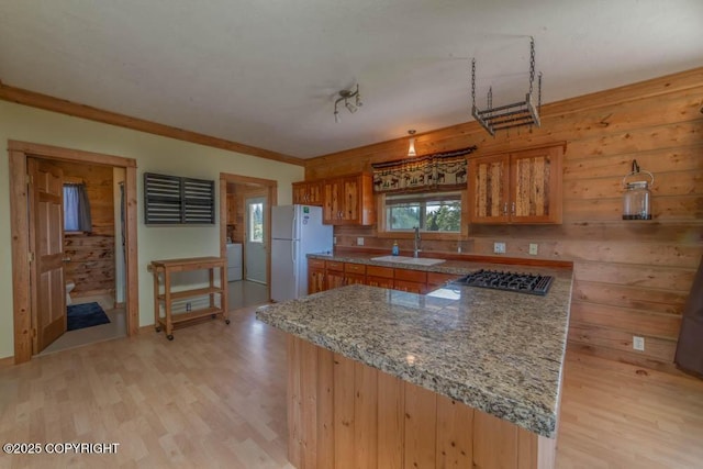 17751 Arcturus Loop, Ninilchik, AK 99639 - kitchen with freestanding refrigerator, brown cabinets, light wood-style flooring, black gas cooktop, and crown molding