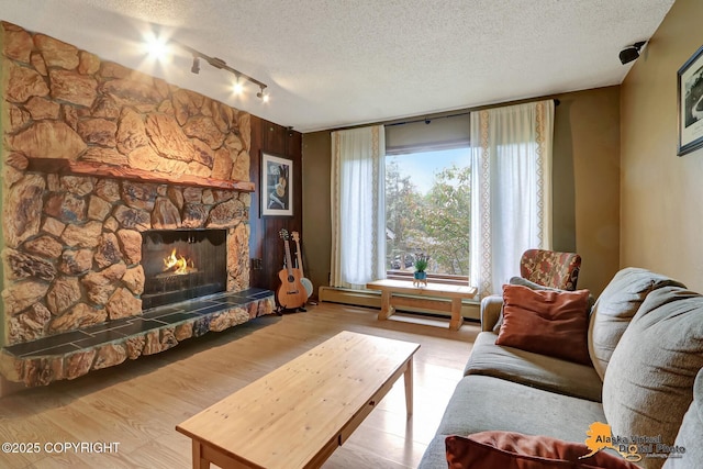 4023 Apollo Dr, Anchorage, AK 99504 - living room featuring track lighting, a baseboard radiator, a textured ceiling, a stone fireplace, and wood finished floors