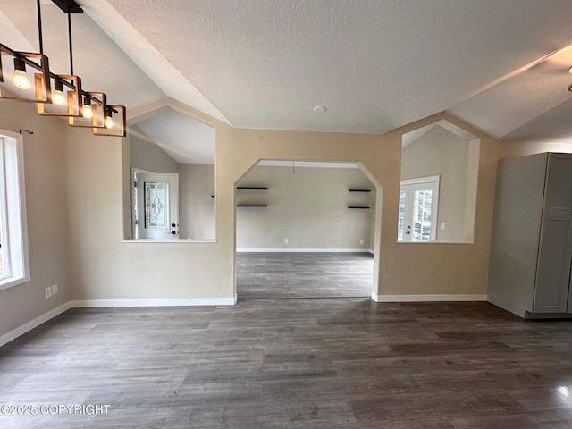 5705 Felix Cir, Homer, AK 99603 - unfurnished living room with plenty of natural light, a textured ceiling, lofted ceiling, dark wood-style floors, and arched walkways