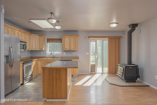 1250 Toolik Dr, North Pole, AK 99705 - kitchen with appliances with stainless steel finishes, light brown cabinets, a center island, a wood stove, and light wood finished floors