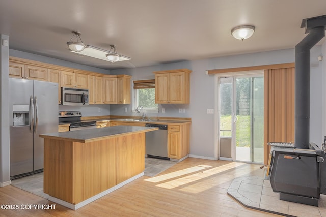 1250 Toolik Dr, North Pole, AK 99705 - kitchen featuring stainless steel appliances, a wood stove, light wood-style flooring, a center island, and light brown cabinets