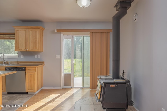 1250 Toolik Dr, North Pole, AK 99705 - kitchen with dishwasher, a wood stove, light brown cabinetry, light wood-type flooring, and light countertops