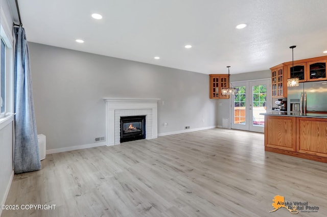 8461 Greenhill Way, Anchorage, AK 99502 - unfurnished living room with light wood-type flooring, a brick fireplace, recessed lighting, and french doors