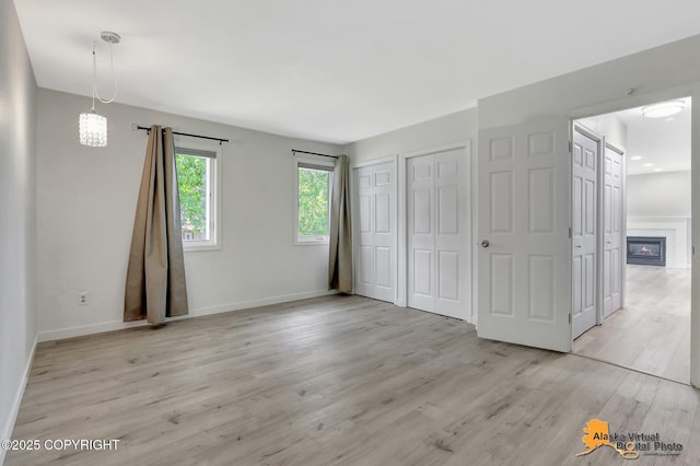 8461 Greenhill Way, Anchorage, AK 99502 - unfurnished bedroom with two closets, light wood-style flooring, and a glass covered fireplace
