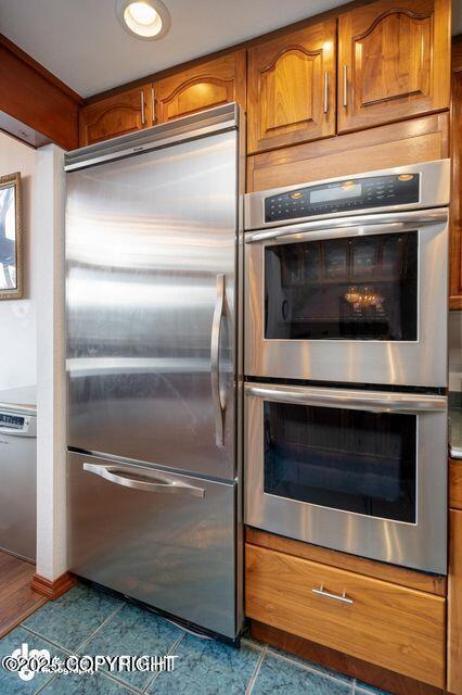 2107 Sorbus Way, Anchorage, AK 99508 - kitchen with stainless steel appliances, brown cabinets, and dark tile patterned flooring