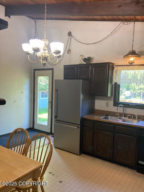 2531 W 79th Ave, Anchorage, AK 99502 - kitchen featuring freestanding refrigerator, a chandelier, beamed ceiling, pendant lighting, and light floors