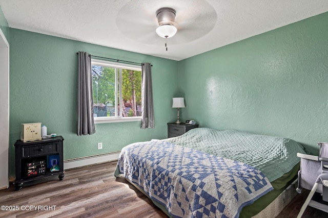 1119 Alder Ave, Kenai, AK 99611 - bedroom featuring a baseboard radiator, a textured wall, wood finished floors, and ceiling fan