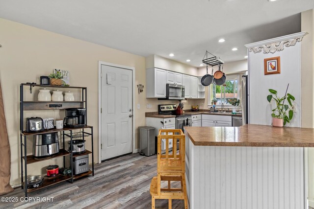 1119 Alder Ave, Kenai, AK 99611 - kitchen with stainless steel appliances, a peninsula, white cabinets, light wood finished floors, and recessed lighting