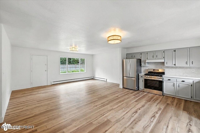 173 W Corral Ave, Soldotna, AK 99669 - kitchen featuring stainless steel appliances, gray cabinetry, baseboard heating, under cabinet range hood, and light wood-style floors