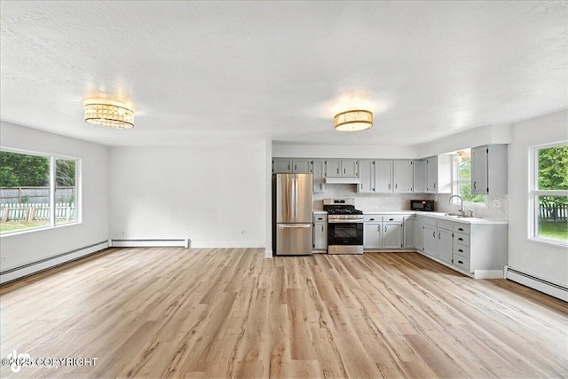 173 W Corral Ave, Soldotna, AK 99669 - kitchen with appliances with stainless steel finishes, gray cabinetry, light countertops, light wood-type flooring, and decorative backsplash