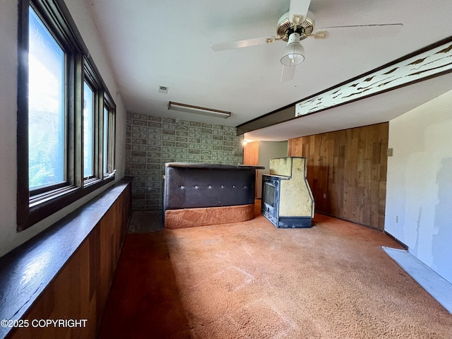8204 E 17th Ave, Anchorage, AK 99504 - unfurnished living room with carpet, a fireplace, wood walls, and ceiling fan