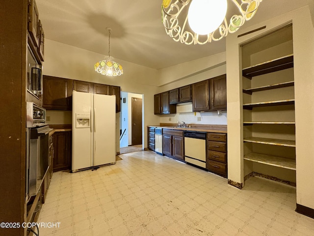 8204 E 17th Ave, Anchorage, AK 99504 - kitchen with white appliances, light floors, dark brown cabinetry, a chandelier, and pendant lighting