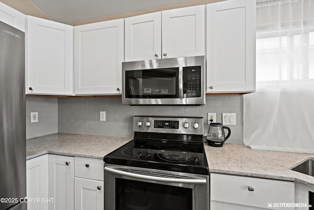 369 Breeze Ct # 13, Anchorage, AK 99515 - kitchen with appliances with stainless steel finishes, white cabinetry, tasteful backsplash, and light stone countertops