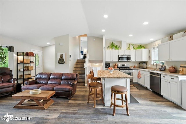 16720 E Maud Rd, Palmer, AK 99645 - kitchen featuring appliances with stainless steel finishes, open floor plan, lofted ceiling, a kitchen bar, and dark wood-style flooring