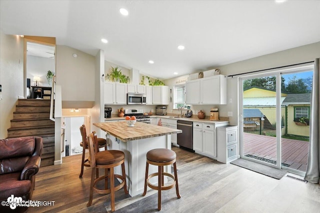16720 E Maud Rd, Palmer, AK 99645 - kitchen with appliances with stainless steel finishes, butcher block countertops, a kitchen breakfast bar, vaulted ceiling, and white cabinetry