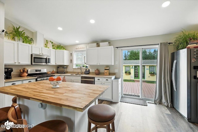16720 E Maud Rd, Palmer, AK 99645 - kitchen featuring appliances with stainless steel finishes, a breakfast bar, wood counters, plenty of natural light, and recessed lighting
