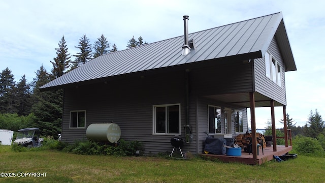 2008 Bickford Cir, Seldovia, AK 99663 - back of property featuring a standing seam roof, oil tank, a metal roof, a lawn, and a patio area