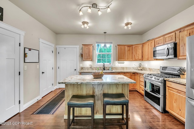 5305 N Caprice Dr, Palmer, AK 99645 - kitchen featuring appliances with stainless steel finishes, dark wood-style flooring, a kitchen island, and a breakfast bar