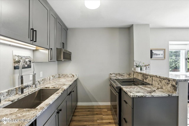 3601 Oregon Dr # 1, Anchorage, AK 99517 - kitchen featuring appliances with stainless steel finishes, a peninsula, gray cabinetry, dark wood-style floors, and light stone countertops
