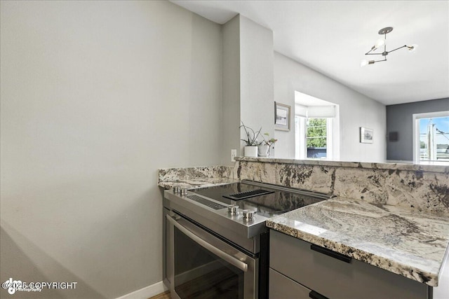 3601 Oregon Dr # 1, Anchorage, AK 99517 - kitchen with electric stove, plenty of natural light, light stone countertops, and a chandelier
